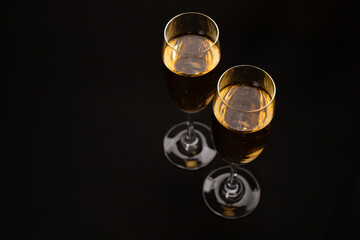 Two glasses of champagne glasses on luxury black background.