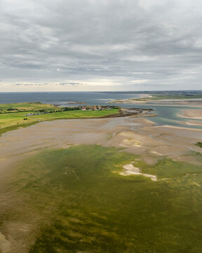 Aerial view of holy island at low tide with serene water and expansive coastline, Berwick-upon-Tweed, England.