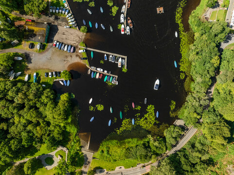 Aerial view of Loch Lomond with tranquil harbour and boats surrounded by lush greenery, Balmaha, Scotland, United Kingdom.