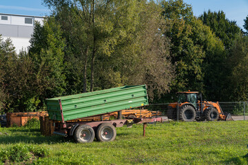 Tractor and trailer parked in a green field during sunny afternoon