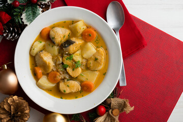 Hake stew with potatoes and carrots. Top view table with Christmas decorations.