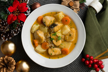 Hake stew with potatoes and carrots. Top view table with Christmas decorations.