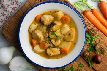 Hake stew with potatoes and carrots. Top view table with  decorations.