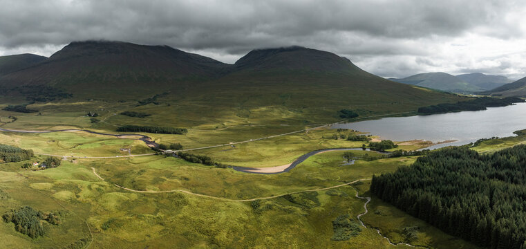 Aerial view of serene Loch Tulla surrounded by majestic mountains and lush greenery, Bridge of Orchy, United Kingdom.