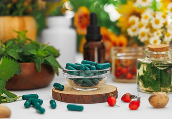 Herbal supplements and natural remedies displayed on a table with fresh flowers and greenery during a sunny afternoon