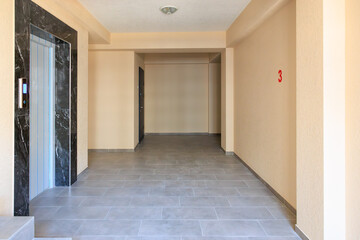 A large, empty hallway with a black and white elevator in the middle