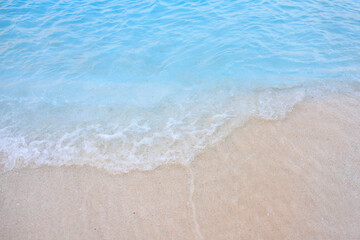 The ocean is calm and blue, with white line in the water