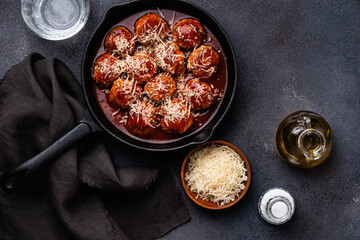 Meatballs with tomato sauce in cast iron pan on gray background, copy space