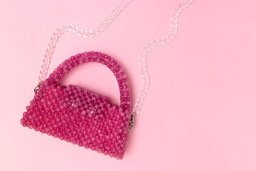Handmade beaded bag with transparent chain on a pink background. Place for text.