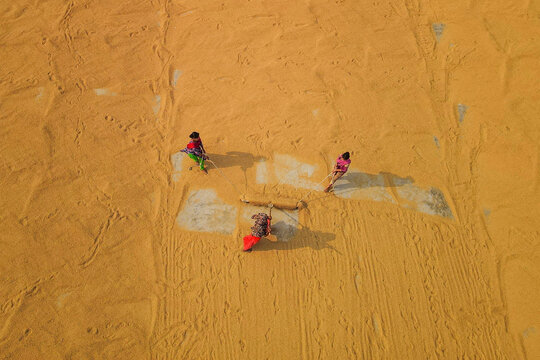 Aerial view of sun dried paddy fields and rice mill with workers, Brahmanbaria, Bangladesh.