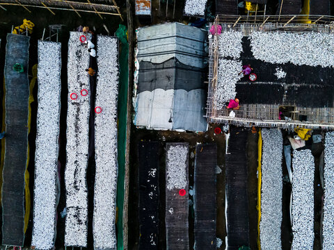 Aerial view of traditional fish processing with busy workers and drying fish in rows, Chittagong, Bangladesh.