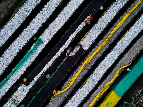Aerial view of vibrant fish drying racks with workers using traditional techniques, Chittagong, Bangladesh.
