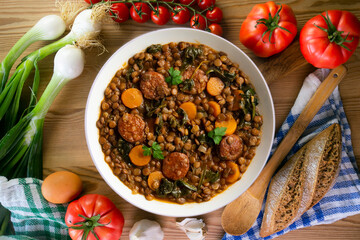 Lentil stew with chorizo, spinach and carrot. Top view table with  decorations.