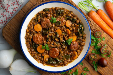 Lentil stew with chorizo, spinach and carrot. Top view table with  decorations.