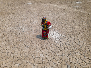 Khulna, Bangladesh - 15 May 2023: Aerial view of a woman collecting water amidst cracked earth in a drought-affected coastal village, Khulna, Bangladesh.