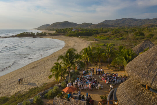 Aerial view of a tropical beach with palm trees and a wedding ceremony near a villa, Troncones, Mexico.