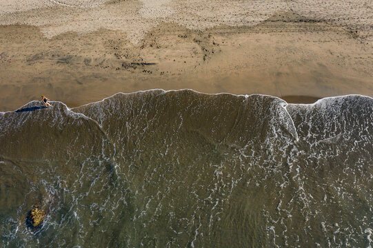 Aerial view of beautiful Playa Troncones beach with waves and a person casting a shadow, Troncones, Mexico.
