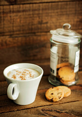 A coffee with milk and cookies on a wooden background