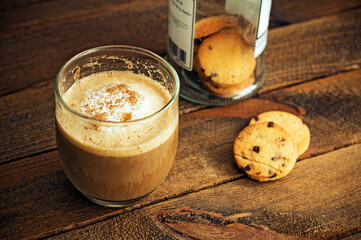 A coffee with milk and cookies on a wooden background