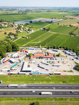 Aerial view of a gas station and motorway with trucks amidst green fields, Santa Maria di Campagna, Cessalto, Treviso, Italy.