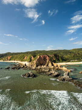 Aerial view of beautiful Adan Beach with rocky shore and cliffs under a clear blue sky, Kunigami Son, Japan.