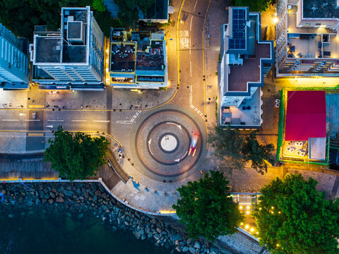 Aerial view of vibrant cityscape at night with illuminated buildings and a roundabout, Chung Hom Kok, Hong Kong.
