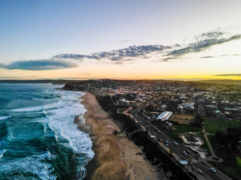 Aerial view of beautiful beach and ocean waves with cityscape and sandy shore at sunset, Chung Hom Kok, Hong Kong.