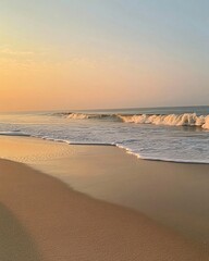 A serene beach scene at sunrise with gentle waves lapping at the shore, casting a golden glow across the sand.