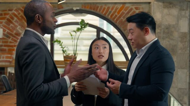 Three multiracial business colleagues in office Asian woman businesswoman document talk angry ignore by two men African Korean businessmen ignoring talking happy unequal rights gender discrimination