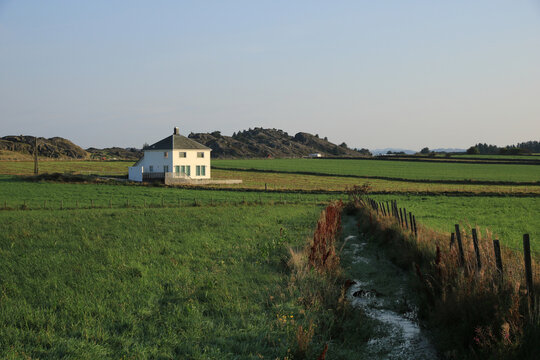 White house surrounded by green meadows and fields, Rogaland, Norway.