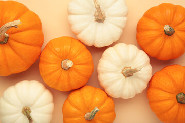 White and orange pumpkins on beige background.