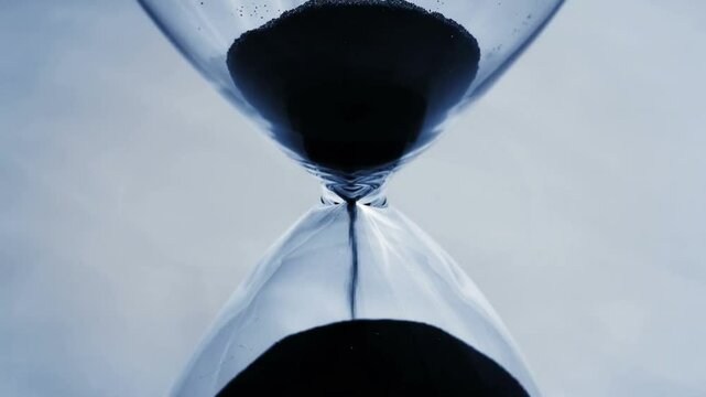 A close shot of countdown beads falling through an hourglass in slow motion