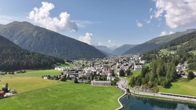 Panoramic aerial view of Davos, Switzerland, on a sunny day, framed by the surrounding natural beauty of the Swiss Alps.