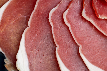 sliced ham with bacon on a board