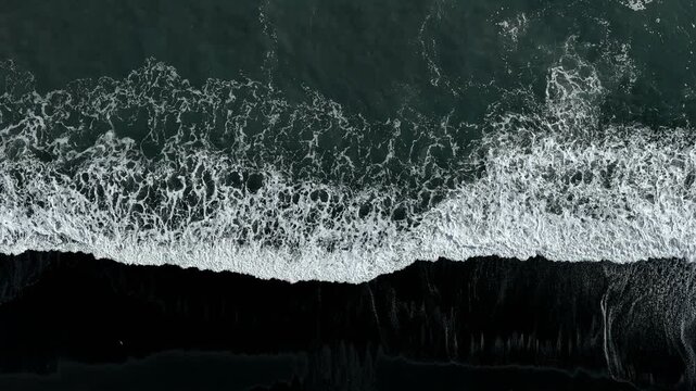 Sea waves breaking on the shore of a black sand beach on Iceland