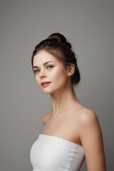 Beautiful young woman in white dress looking to the side, isolated on gray background