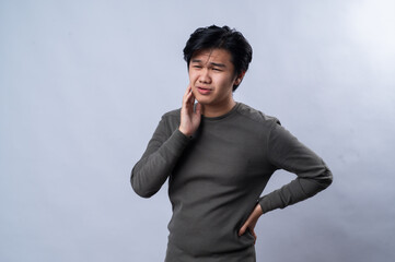 An Asian man is leaning on one hand with a bored or tired expression, slightly pouting, wearing a...