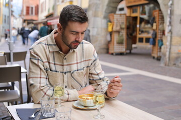 Handsome man eating in European cafe terrace 