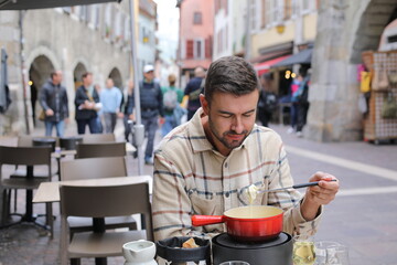 Handsome man enjoying a fondue in Europe 