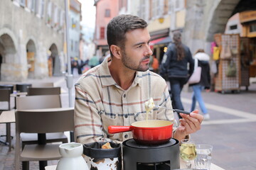 Handsome man enjoying a fondue in Europe 