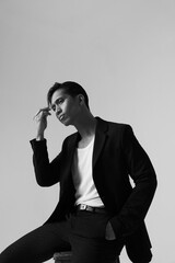 Black and white portrait of thoughtful young asian man posing over white background. Vertical.
