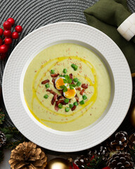 Cream of green beans with Iberian ham and quail egg. Top view table with Christmas decoration.