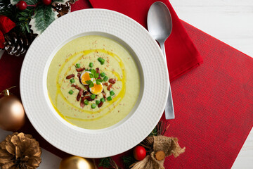 Cream of green beans with Iberian ham and quail egg. Top view table with Christmas decoration.