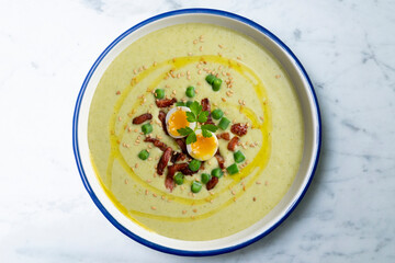 Cream of green beans with Iberian ham and quail egg. Top view table with  decoration.