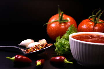 ingredients for making ketchup. ketchup in a white bowl on the table with tomatoes and parsley.