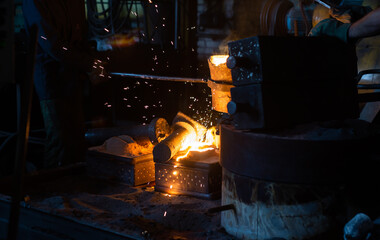 Pouring molten metal into a sand mold in the foundry shop of metallurgical plant