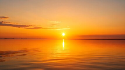 Fototapeta premium The sun sets in a brilliant golden display over a placid sea, with a warm, amber glow spreading across the horizon. The clear, unobstructed sky enhances the calm, serene atmosphere, and the 