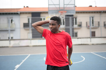 African boy stretching alone before playing basketball outdoors