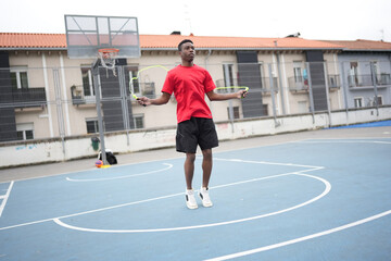 Fototapeta premium African man skipping rope in an urban basketball court
