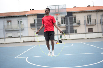 Obraz premium African man jumping rope warming up in basketball court